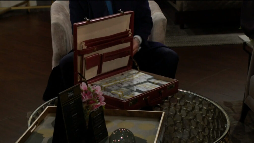 Jack sets down a briefcase full of money on the coffee table in Jeremy Stark's hotel room