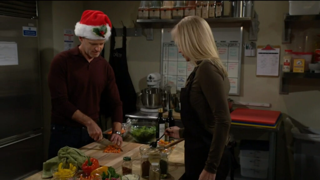 In Society's kitchen, Tucker - in a Santa hat - and Ashley prepare dinner