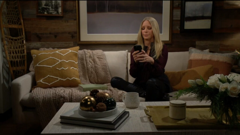 Christine sits alone in her apartment on the couch, looking at her phone