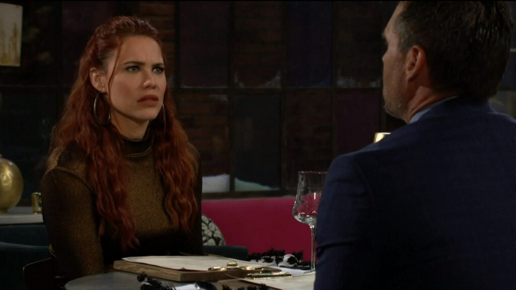 Sally looks concerned as she speaks with Nick while sitting at a table in Society