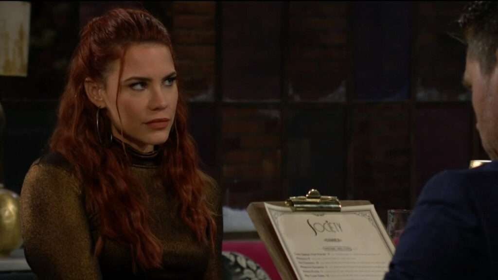 Sally looks at Adam as she sits at the table with Nick