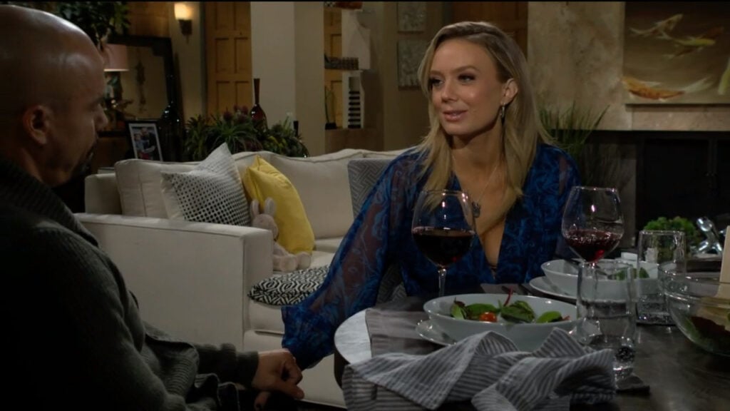 Abby and Devon hold hands as they sit at the dinner table in his living room
