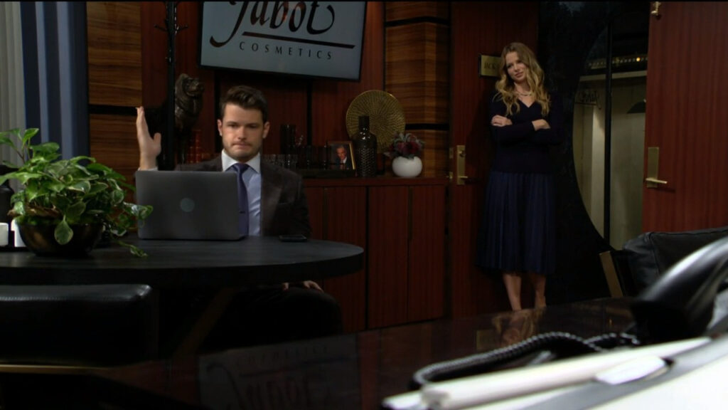Kyle is sitting at his desk working on a laptop, while Summer stands in the doorway to his office
