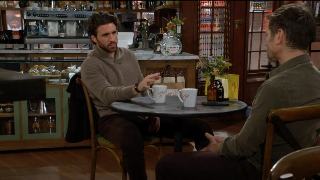 Chance gestures as he talks with Daniel in the coffee shop