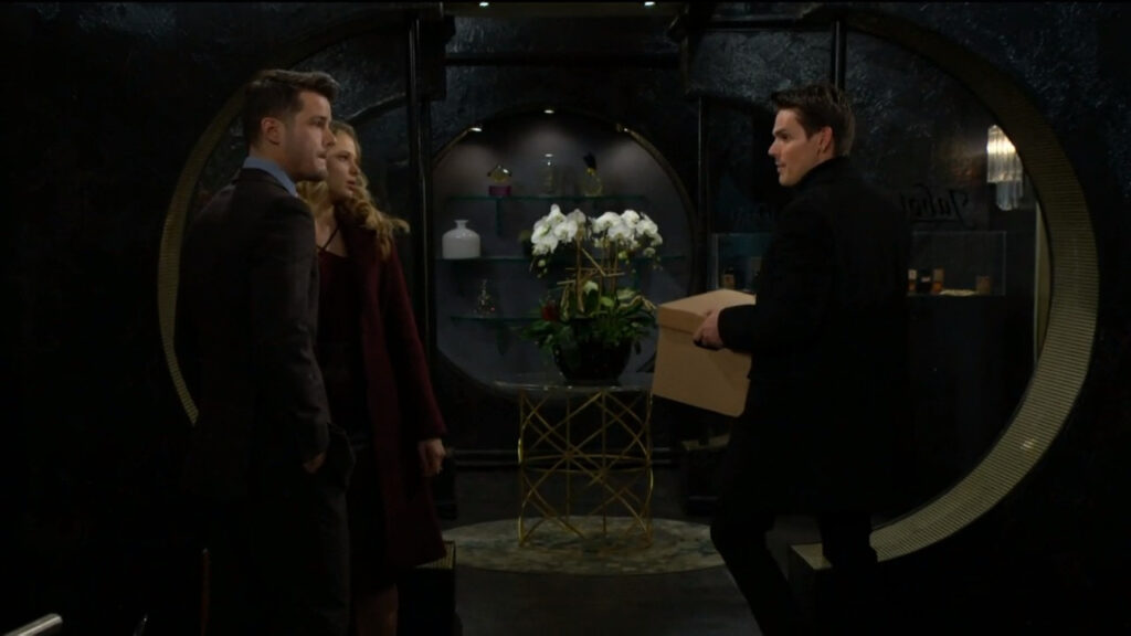 Adam carries a box and talks to Kyle and Summer in the lobby of Jabot