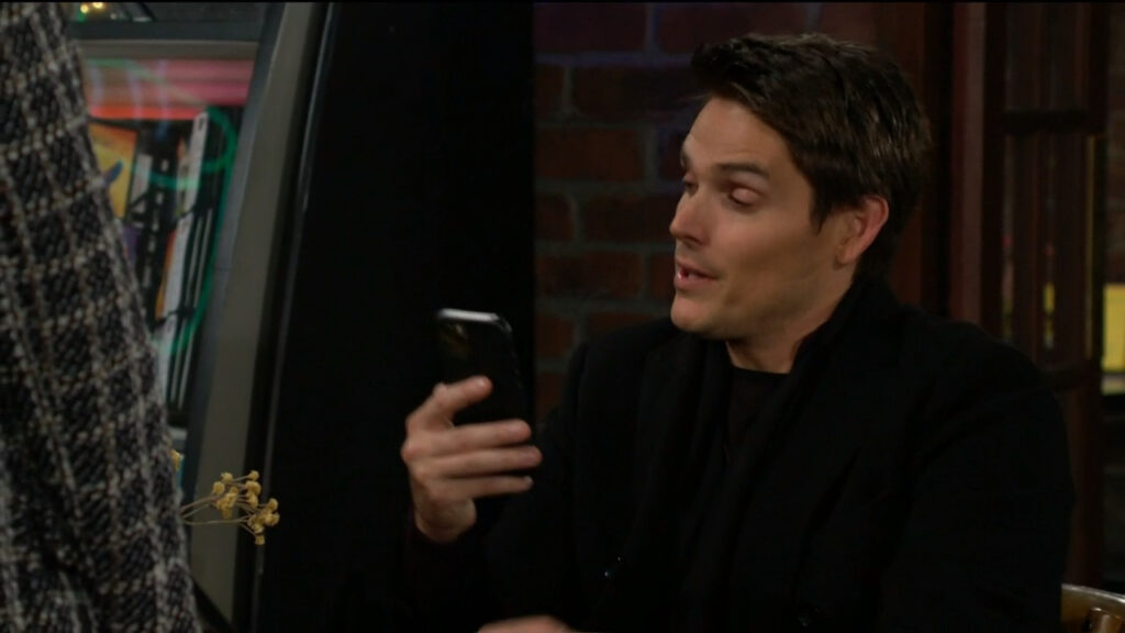 Adam looks at the baby pictures on Mariah's phone