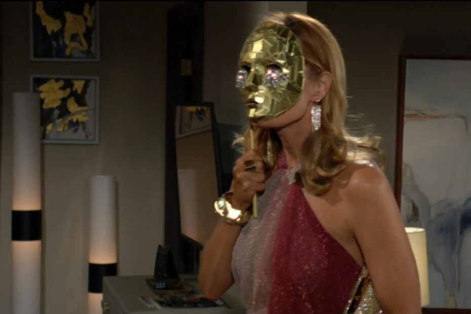 Phyllis holds up a golden mask with gems for teardrops