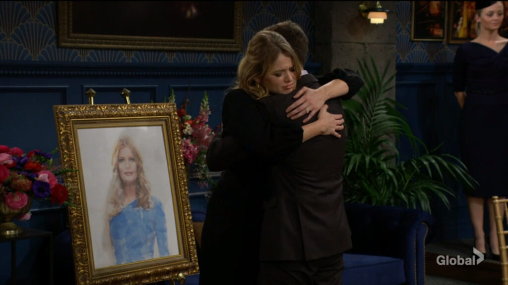 Summer and Daniel hug in front of Phyllis's portrait