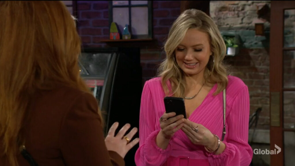 Abby smiles as she looks at pictures of Aria on Mariah's phone