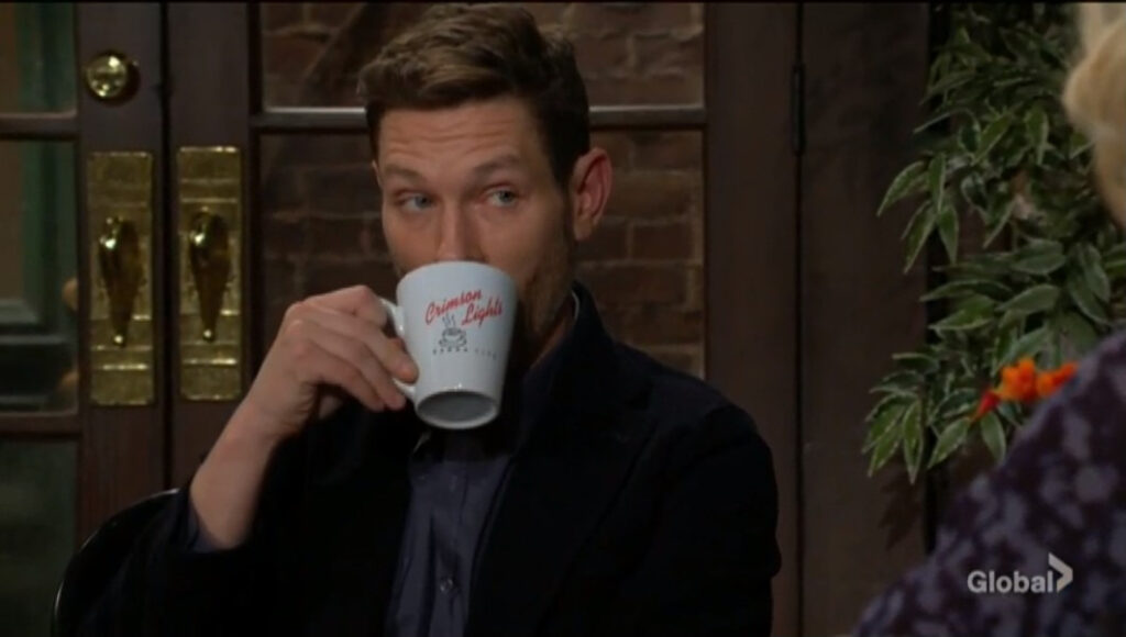 Daniel sips from a Crimson Lights mug as he speaks with Lucy