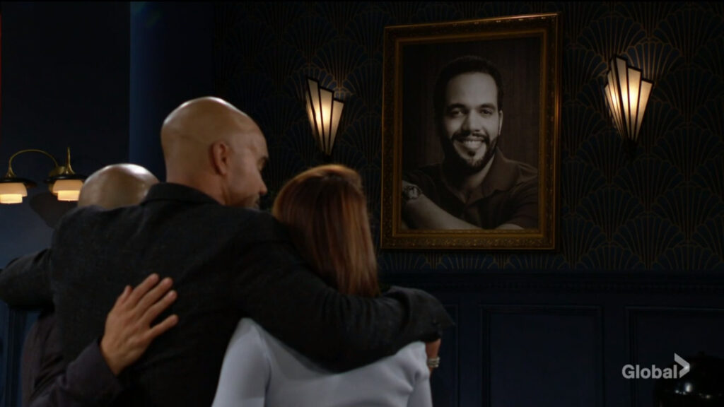 Devon, Malcolm, and Lily hug as they look at Neil's portrait.