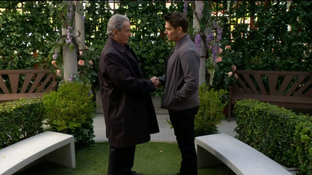 Victor and Adam shake hands in the park.