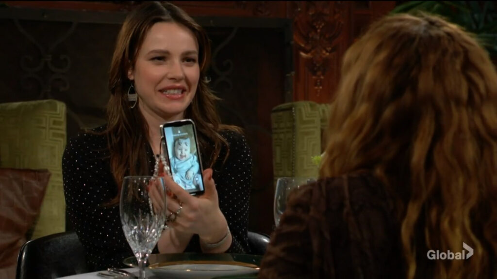 Tessa laughs as she shows Mariah a photo of Aria on her phone.