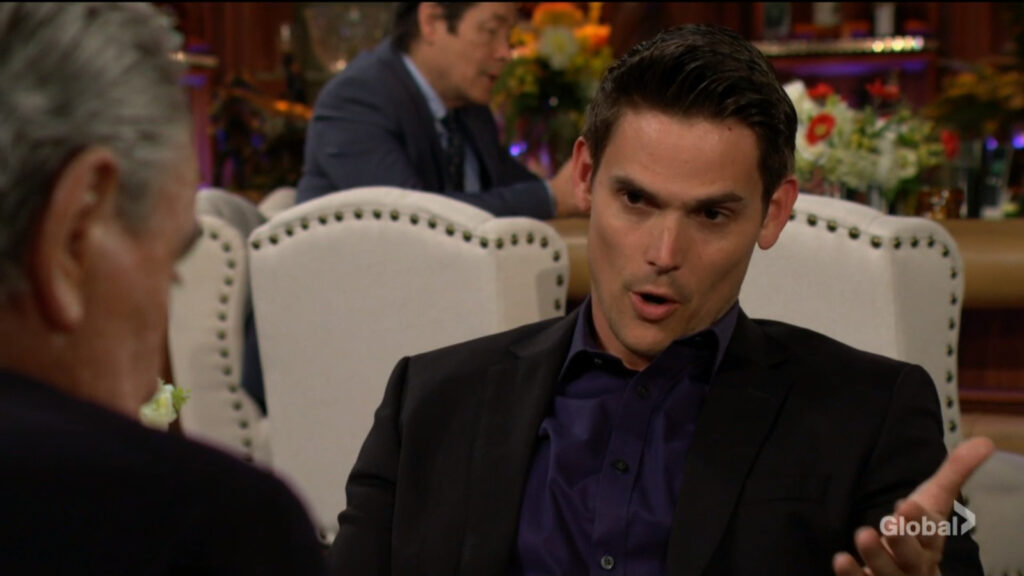 Adam gestures as he sits and talks with Victor.