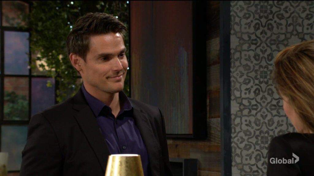 Adam smiles at Victoria as they talk.