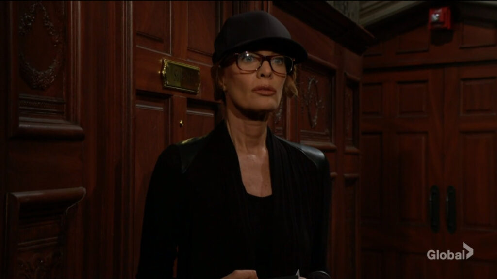 A disguised Phyllis stands in the corridor outside her hotel room.