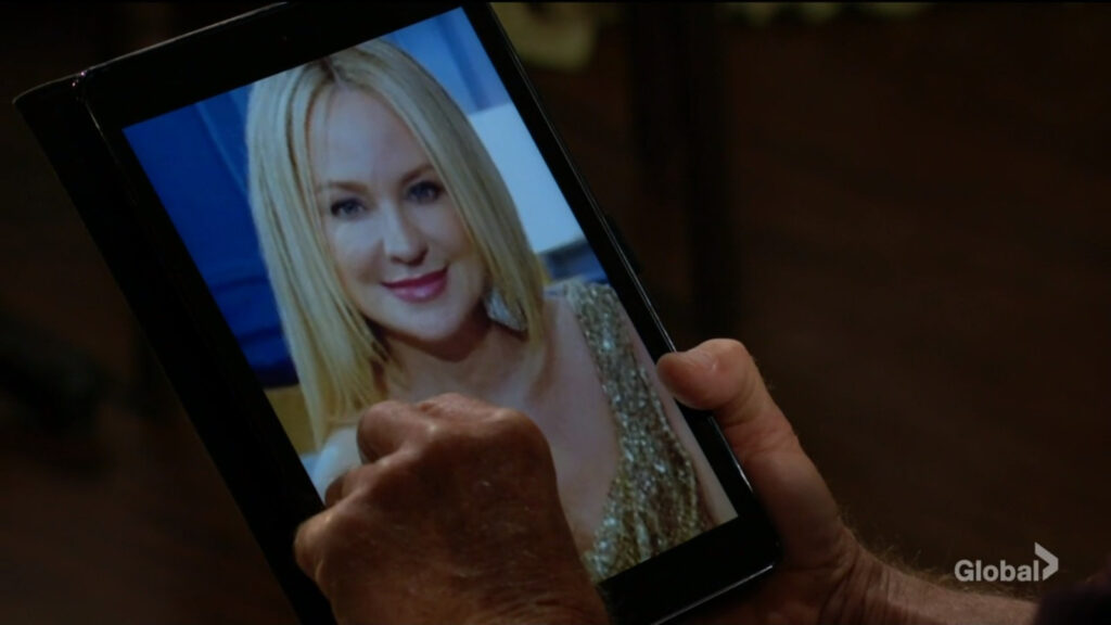 Cameron zooms in on a picture of Sharon on a tablet.