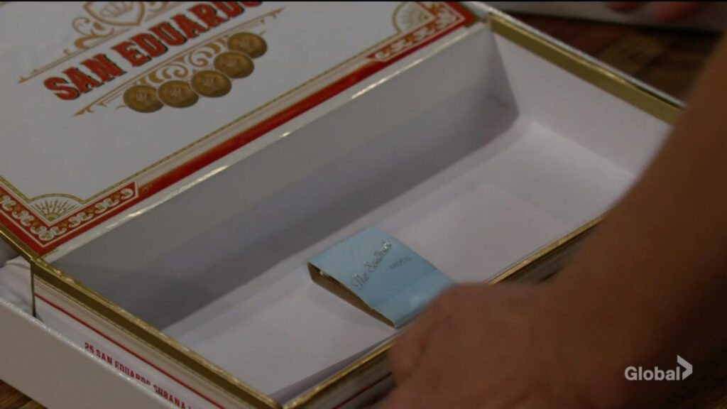 Sharon opens the cigar box to reveal a blue pack of matches.
