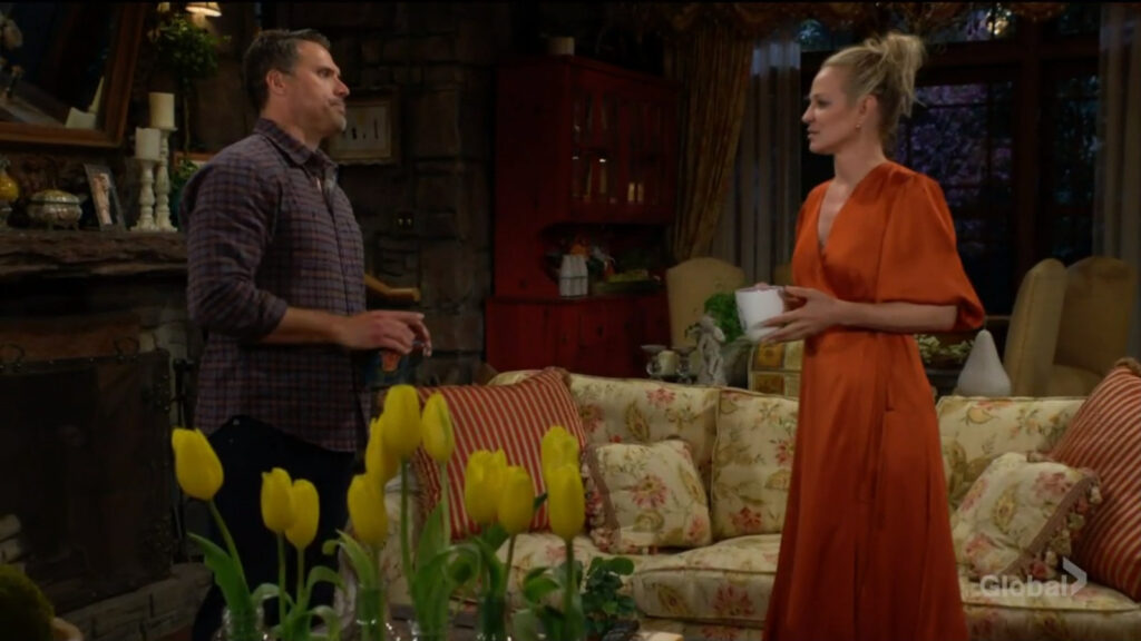 Sharon hands Nick a cup of coffee as she talks to him in her living room.
