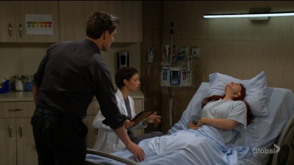 Sally clutches her stomach as she lies on a hospital bed.