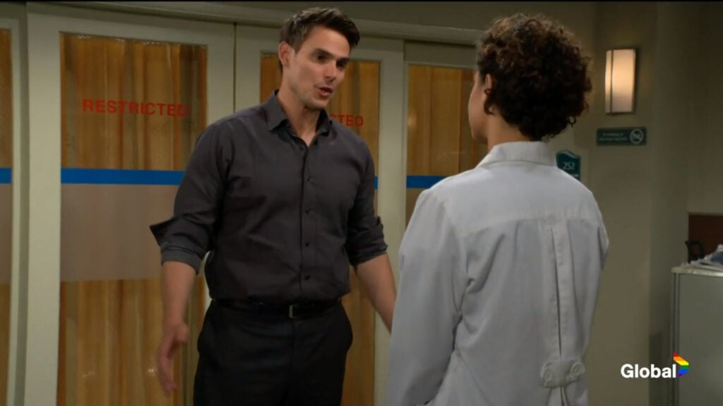 Adam talks with Elena in the corridor.