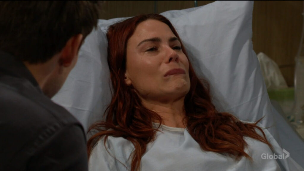 Sally lies in bed, stricken with grief as Adam talks with her.
