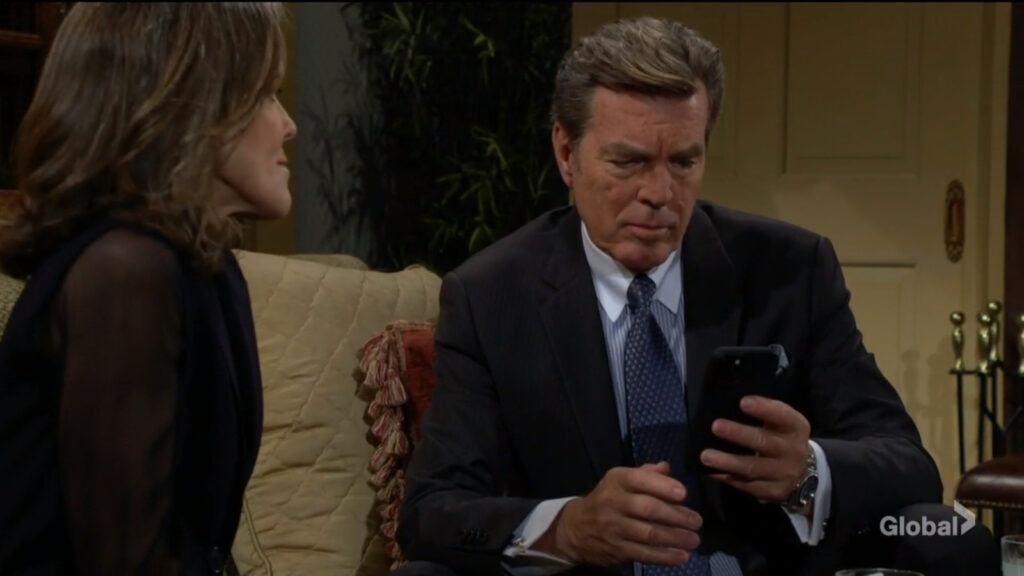 Jack looks at his phone as Diane looks on.
