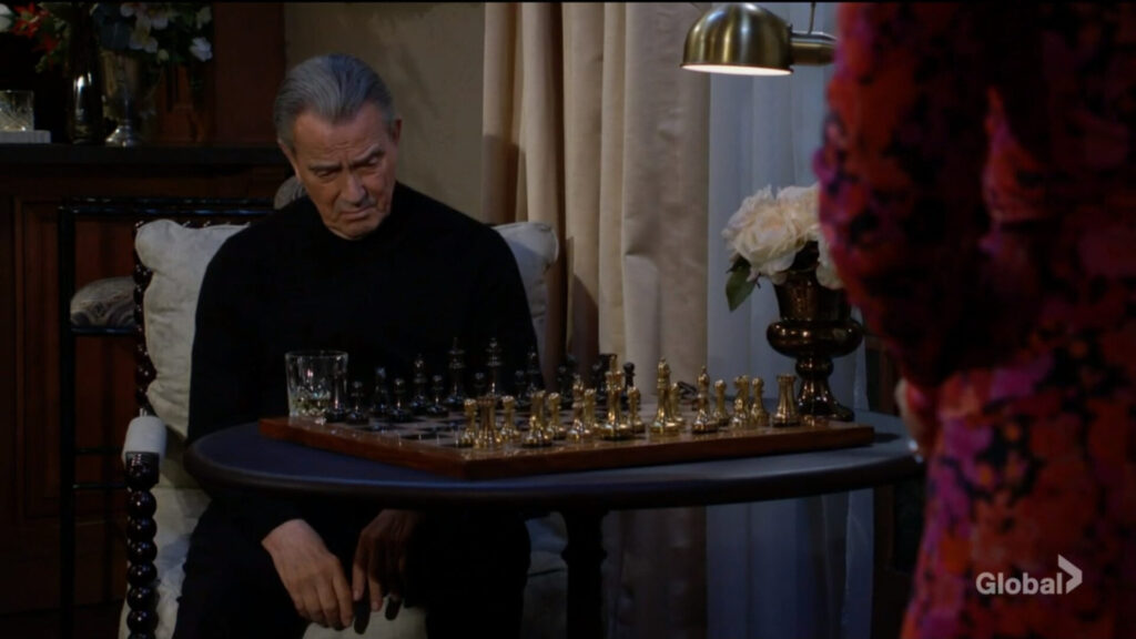 Victor sits at his chess table with a drink in front of him.