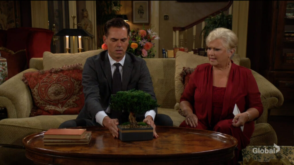 Billy places a bonsai on the table as Traci looks on.