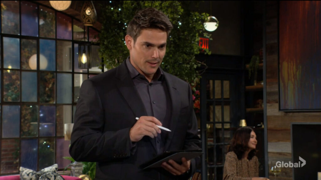 Adam holds a pen and notebook.