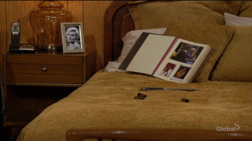 Eve's picture, a photo album, a knife, and vials lie on the bed.