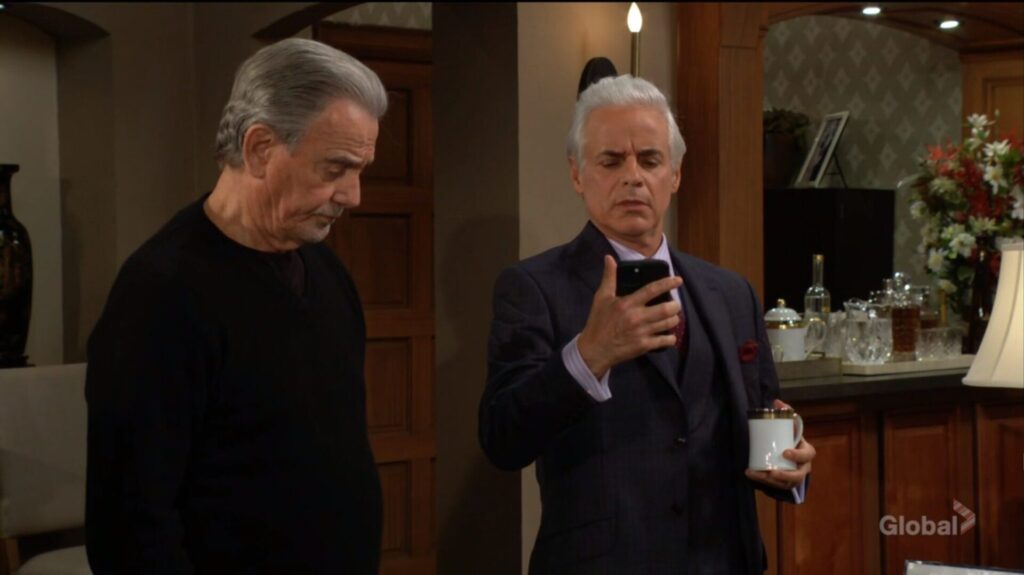 Michael looks at his phone as Victor stands beside him.