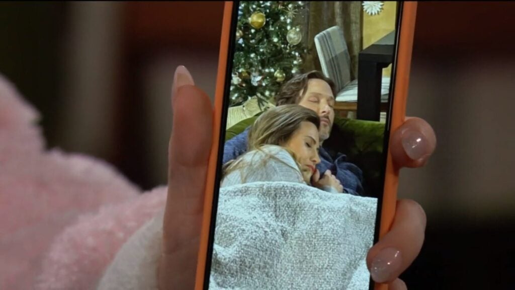 Lucy's phone with a picture of Daniel and Heather sleeping on the couch.
