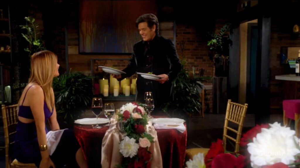 Phyllis sits at a table while Danny serves her.