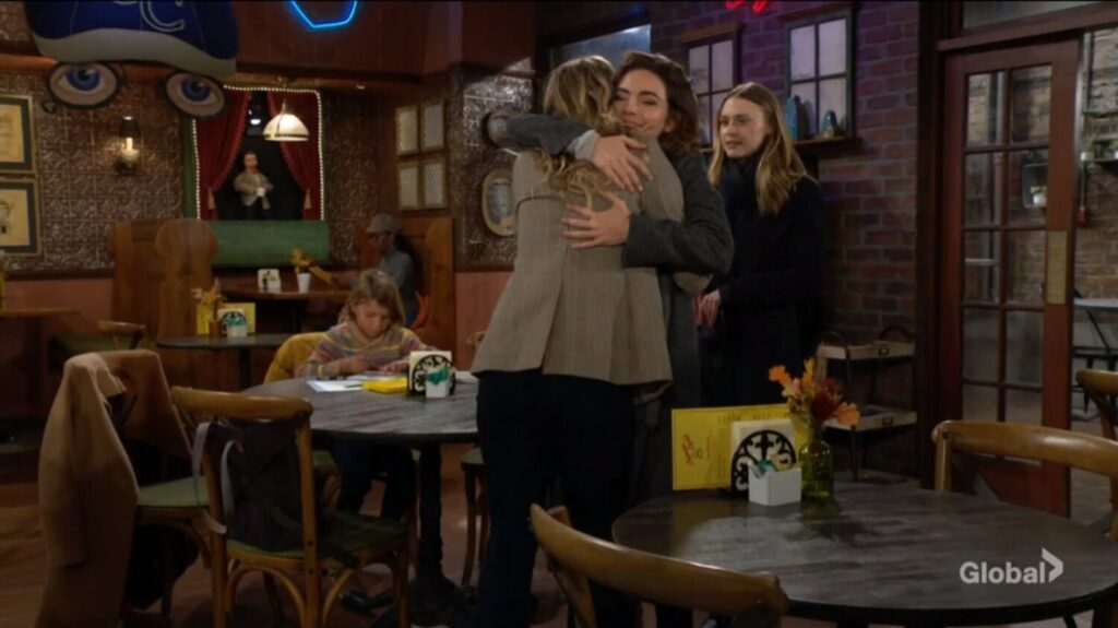 Victoria and Summer hug while Claire looks on. Harrison is sitting at a table coloring.
