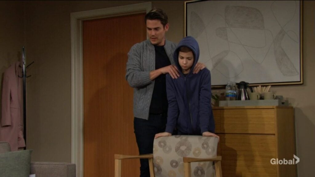Adam puts his hands on Connor's shoulders.