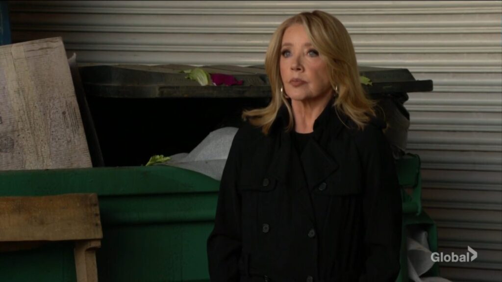 Nikki Newman stands in front of a dumpster.