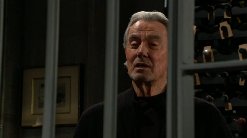 Victor Newman smiles through the bars of a cell.